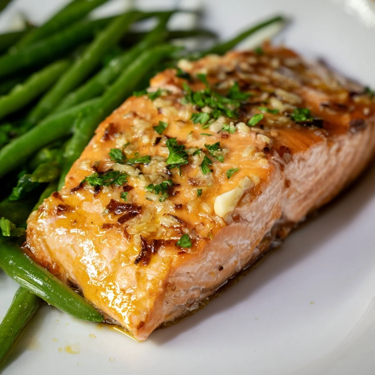 Golden-baked salmon fillets with green beans and lemon wedges on a baking sheet, perfect for weeknight dinner.