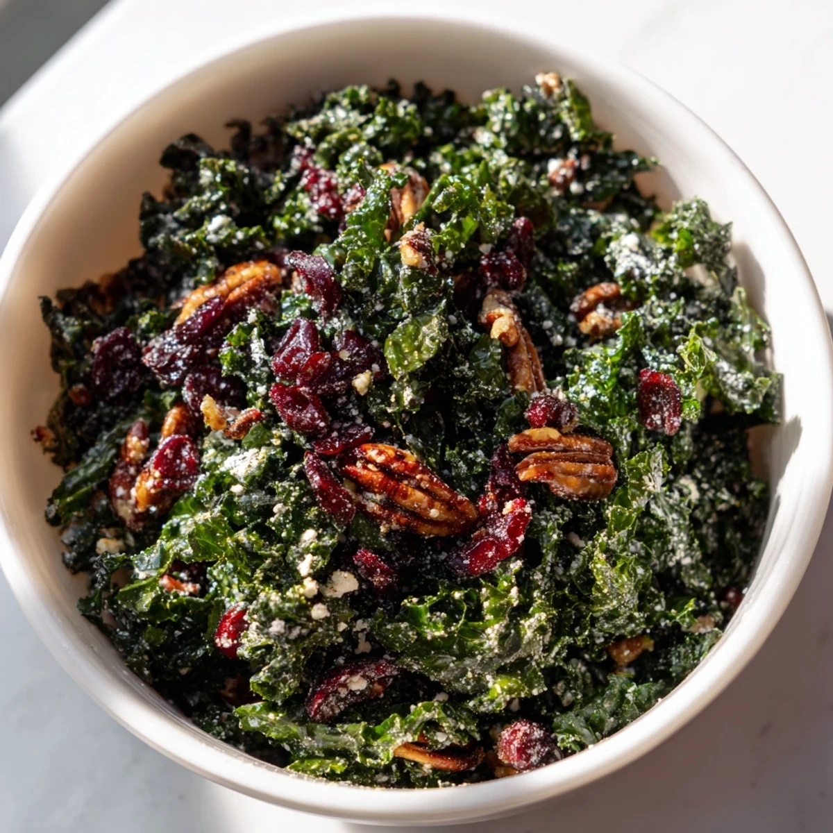 Fresh, vibrant Winter Kale Salad with cranberries, toasted pecans, sliced apple, and tangy citrus dressing in a rustic bowl.