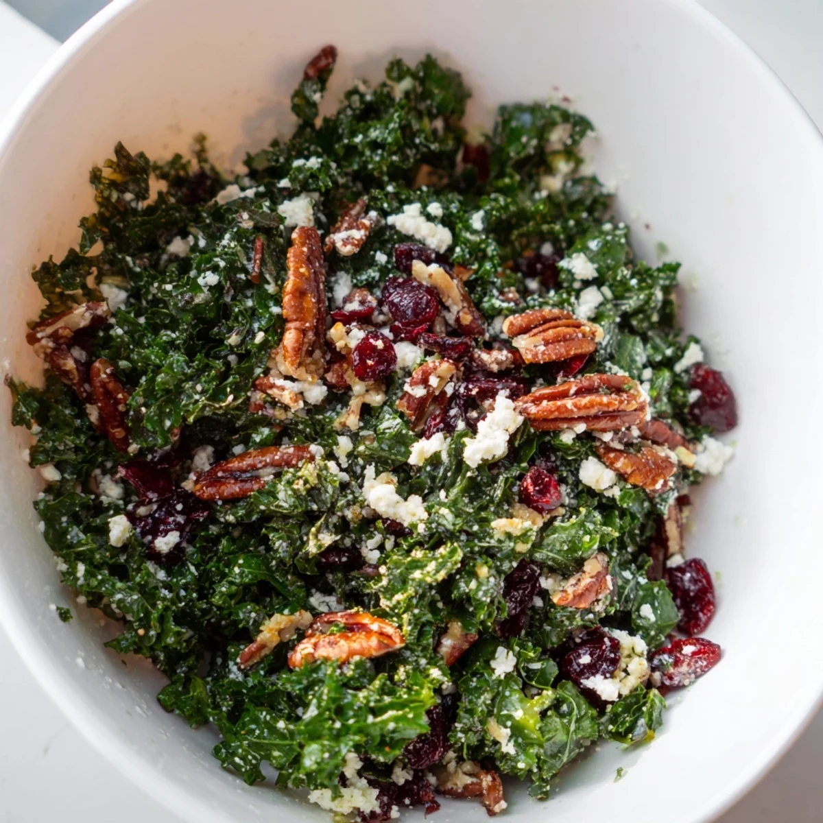 Garnished Winter Kale Salad with cranberries and crumbled feta, tossed in a citrus dressing, ready for a healthy lunch.