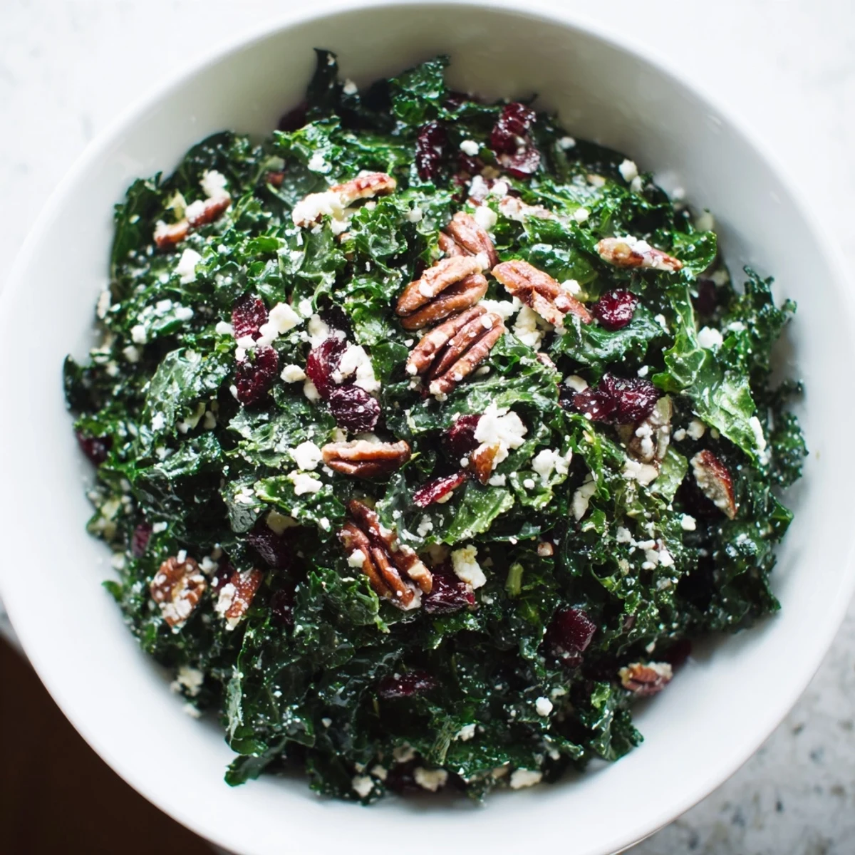 Healthy Winter Kale Salad with kale, dried cranberries, toasted nuts, and goat cheese, served as a festive side dish.