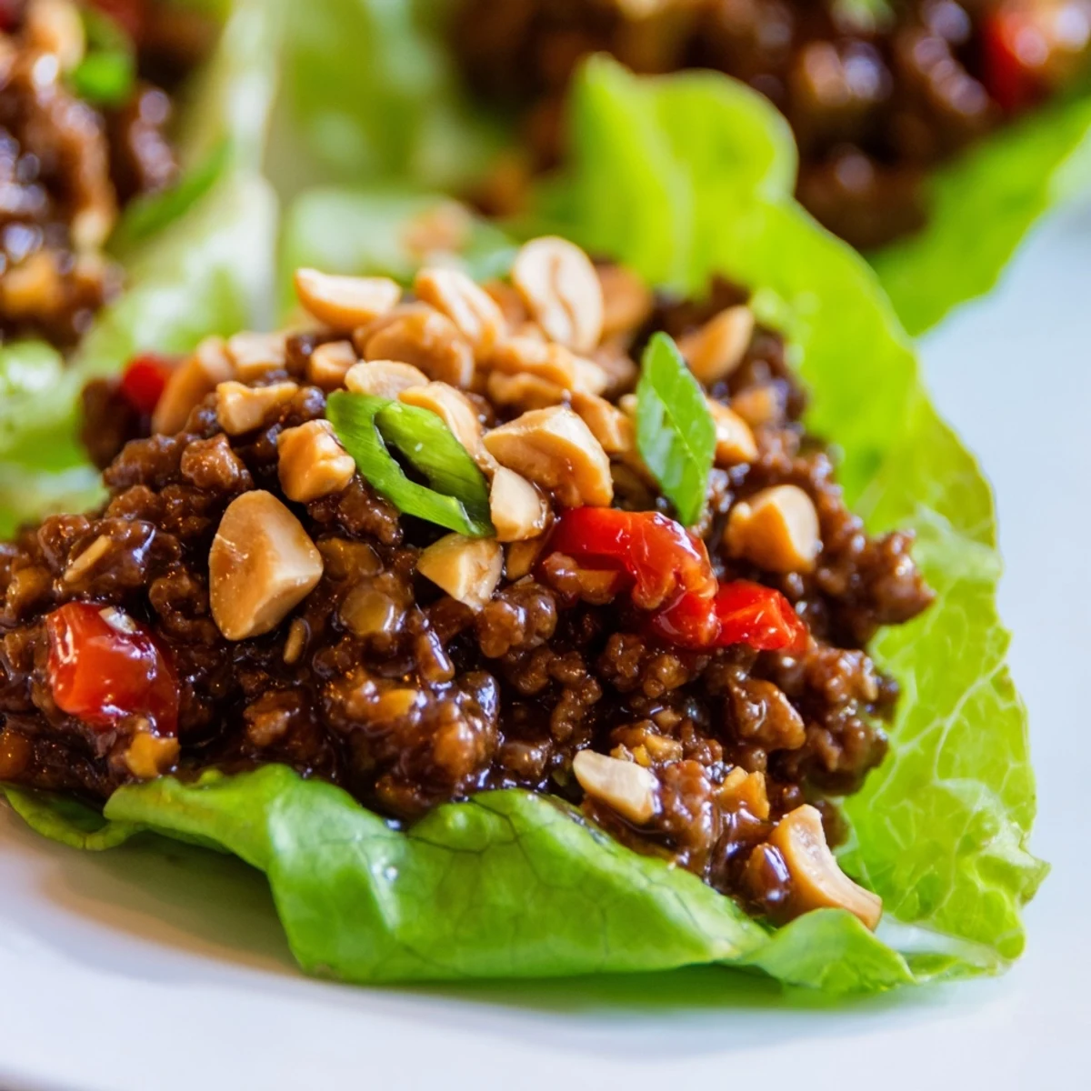 Freshly cooked beef filling steams inside crisp Bibb lettuce wraps, topped with chopped peanuts and sliced green onions.