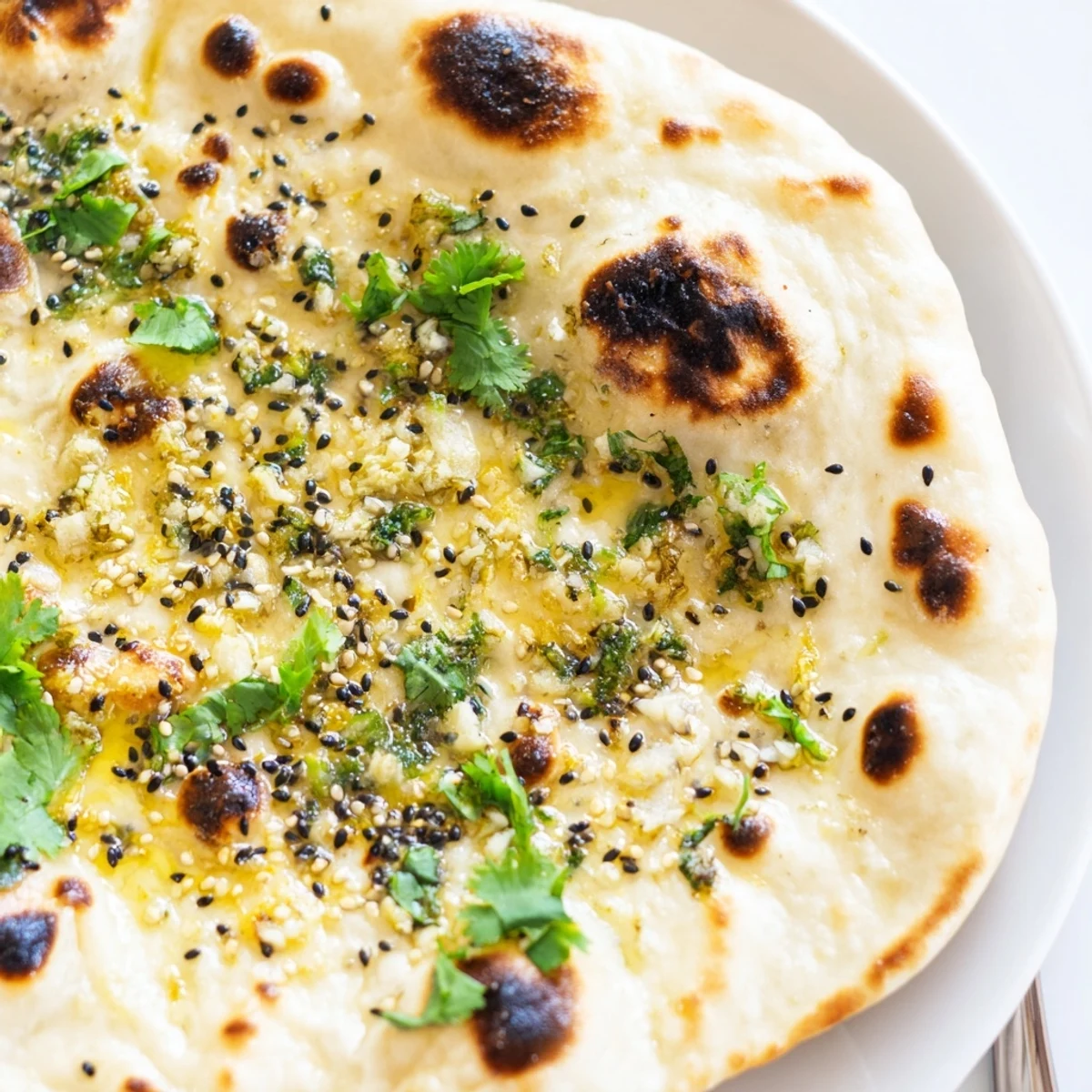 Golden Garlic Naan Bread with Nigella Seeds sizzling in a hot skillet, bubbling and charred with fresh garlic butter.