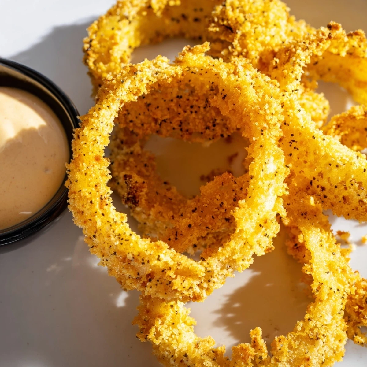 Homemade Crispy Air Fryer Onion Rings with Dip served hot alongside steak and corn on the cob, perfect for game day snacking.
