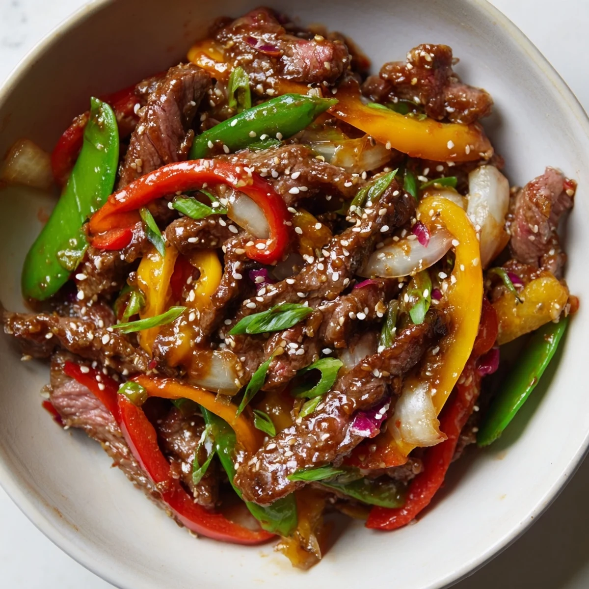 Vivid Spicy Beef Stir Fry plated with toasted sesame seeds and fresh spring onions for a flavorful dinner.