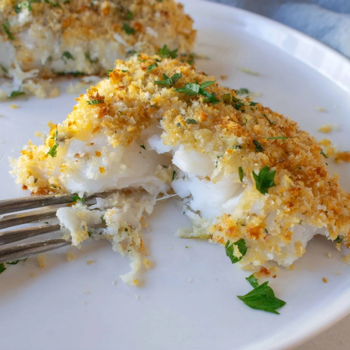 Golden-brown Baked Cod with Panko Crust, flaky and tender, served with lemon wedges on a rustic plate.  