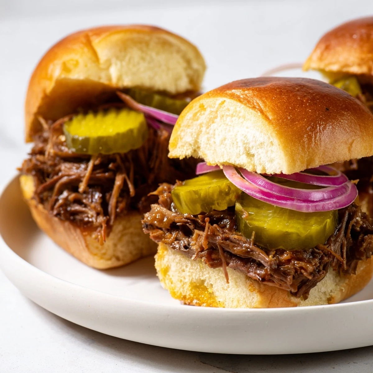 Buttery toasted slider buns stuffed with saucy beef, tangy pickles, and crisp onion rings.