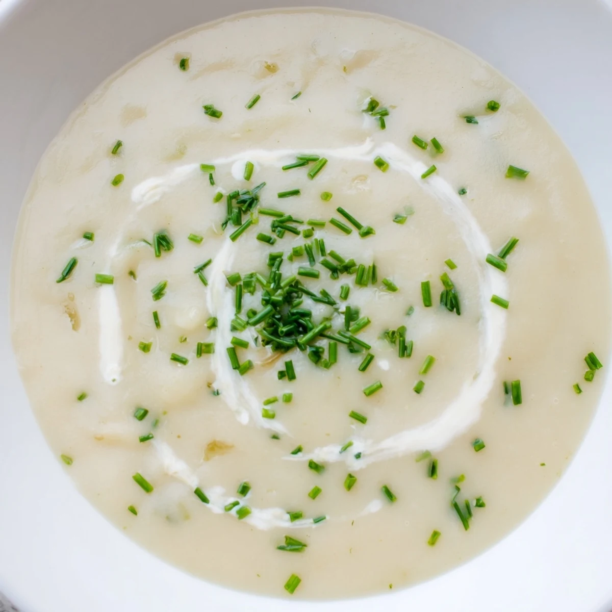 Creamy Potato Soup with Chives in a rustic bowl, garnished with fresh chives and a drizzle of heavy cream.