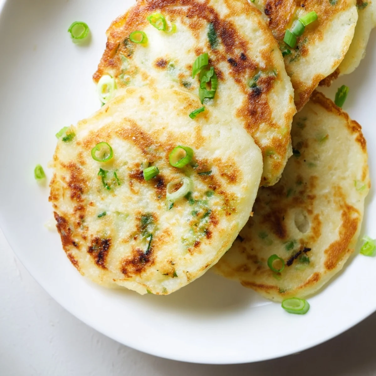 Golden-brown Irish Boxty Potato Pancakes with Scallions sizzling in a skillet, showing a crispy exterior and soft potato interior.  