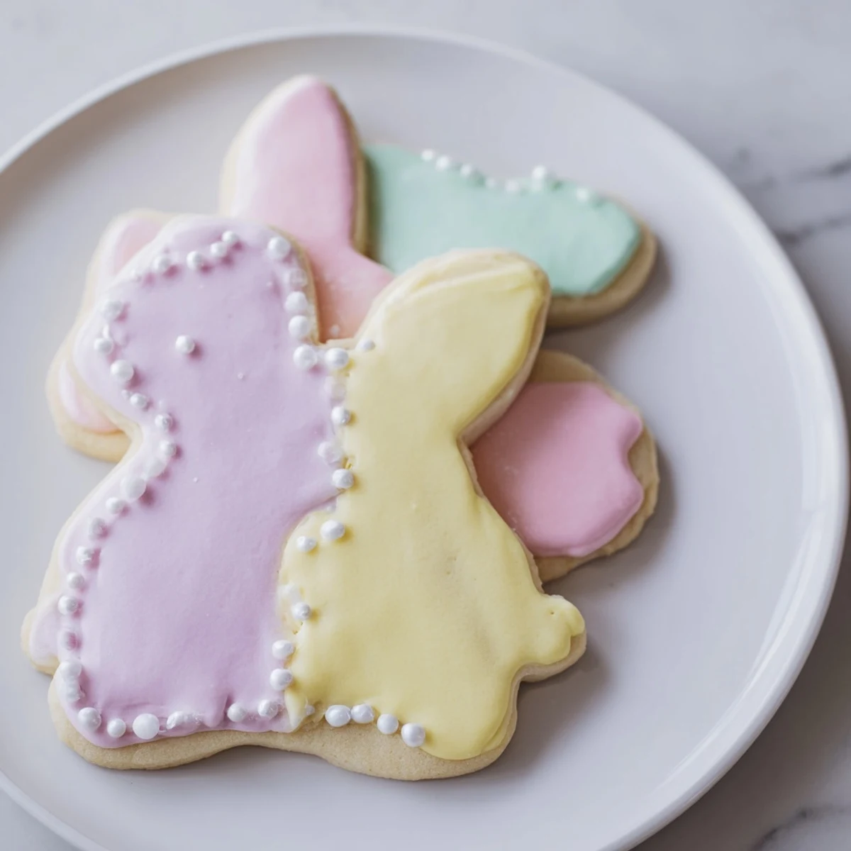 Close-up of decorated Easter Bunny Sugar Cookies showing detailed royal icing patterns and edible pearls.