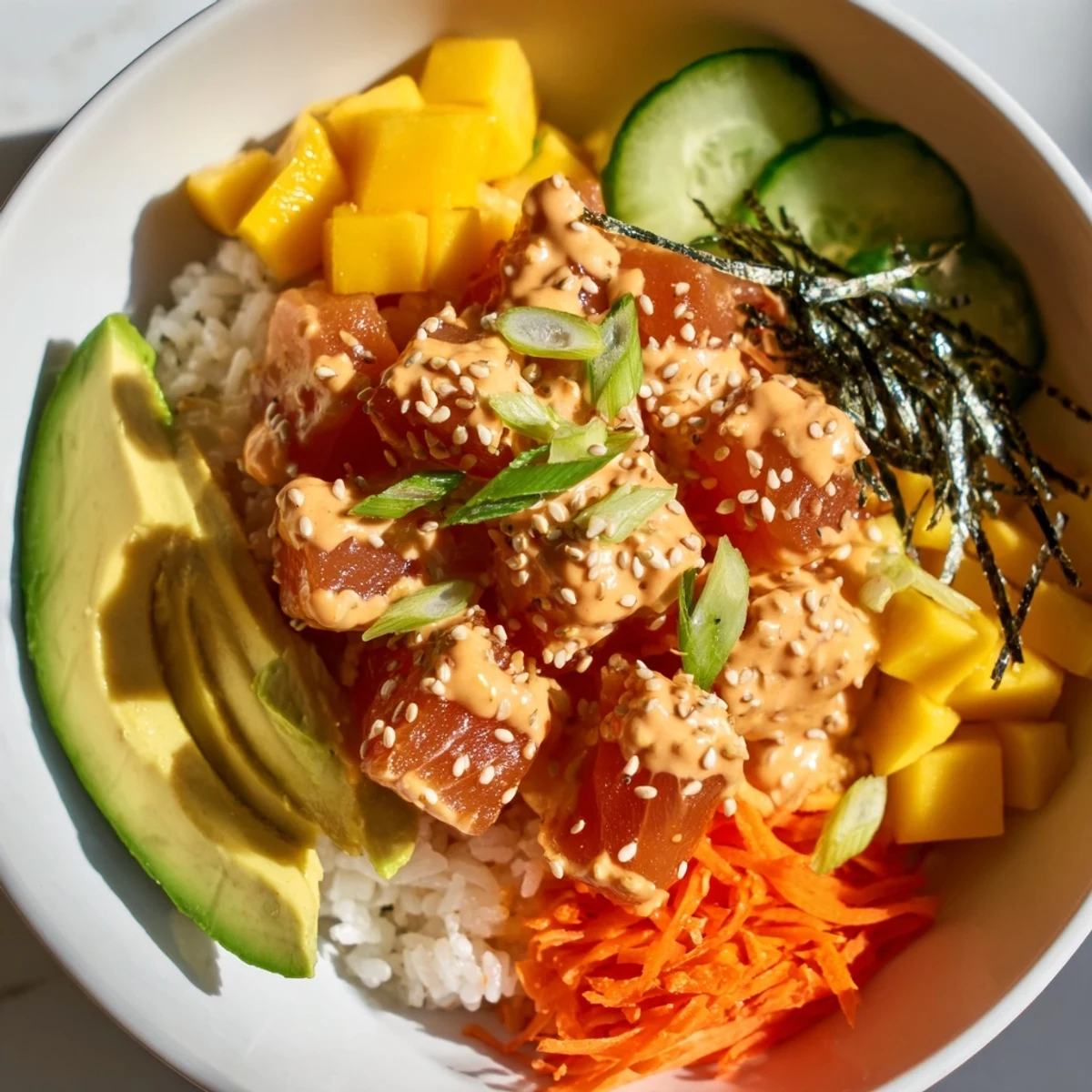 Fragrant sushi rice forms the base of this refreshing Spicy Tuna Poke Bowl, loaded with sashimi-grade tuna, sweet mango, and garnishes like sesame seeds and crispy onions.