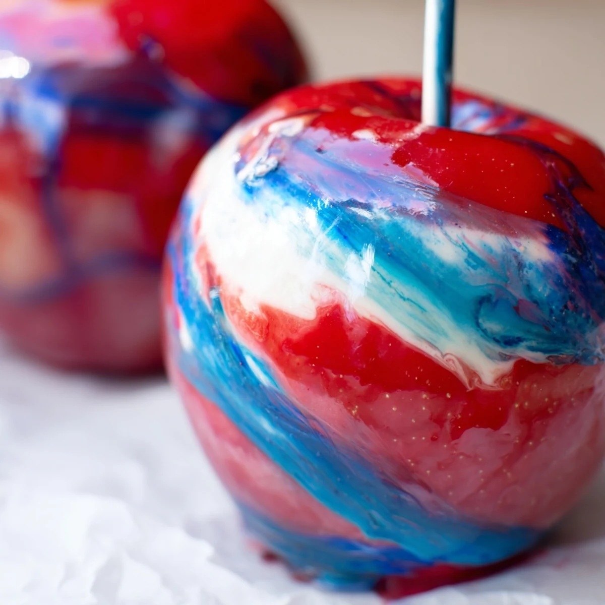 Marbled effect candy apples ready to serve with red blue and white swirls against a dark slate background.