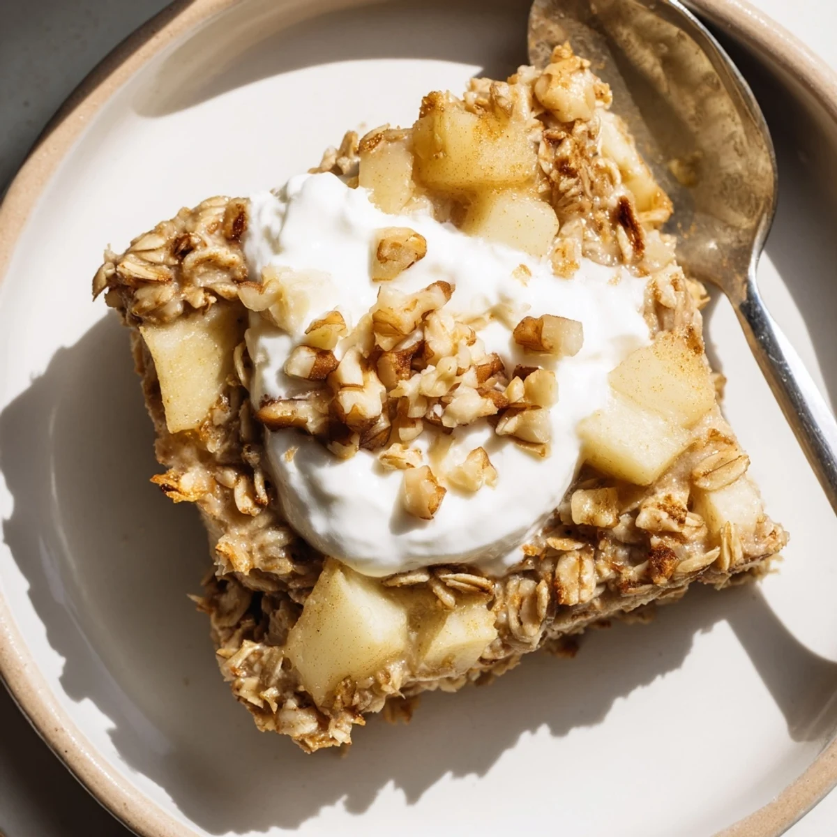 Homemade Baked Apple Oatmeal With Greek Yogurt served in a dish with maple syrup and cinnamon.