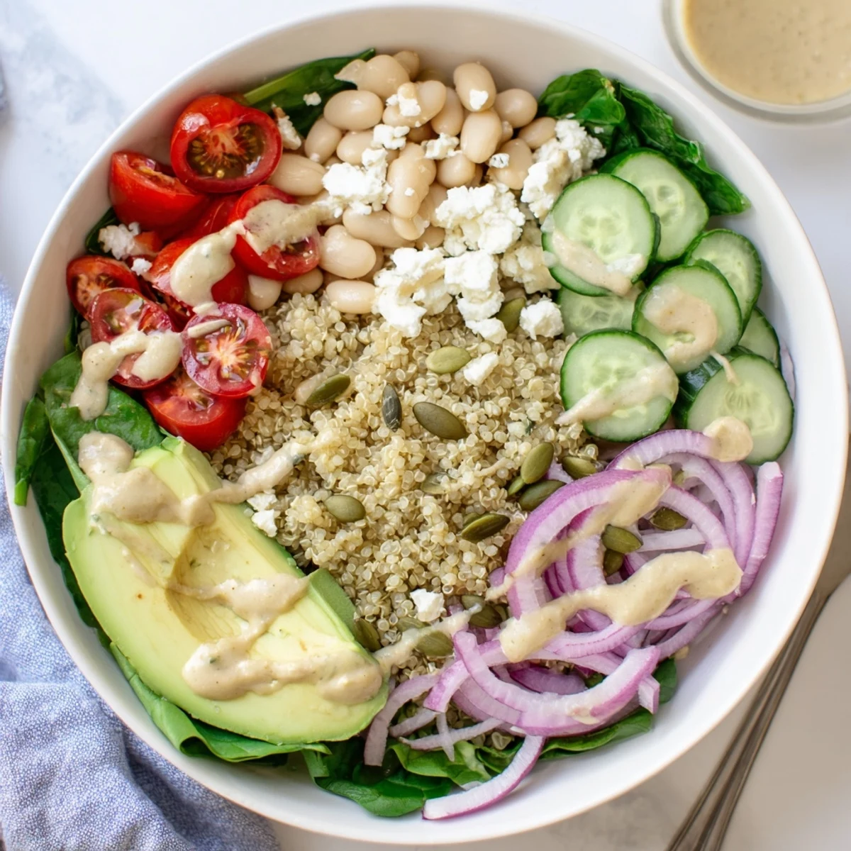 Garnished Spinach & White Bean Ultimate Protein Power Bowl drizzled with tangy lemon tahini dressing.