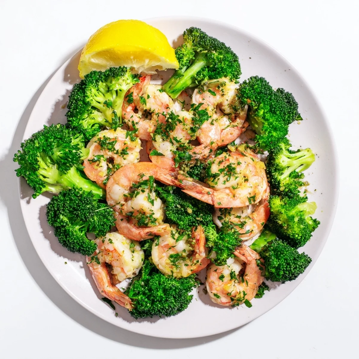 Close-up of juicy shrimp and crisp steamed broccoli coated in a sweet and garlicky butter sauce, garnished with fresh parsley.