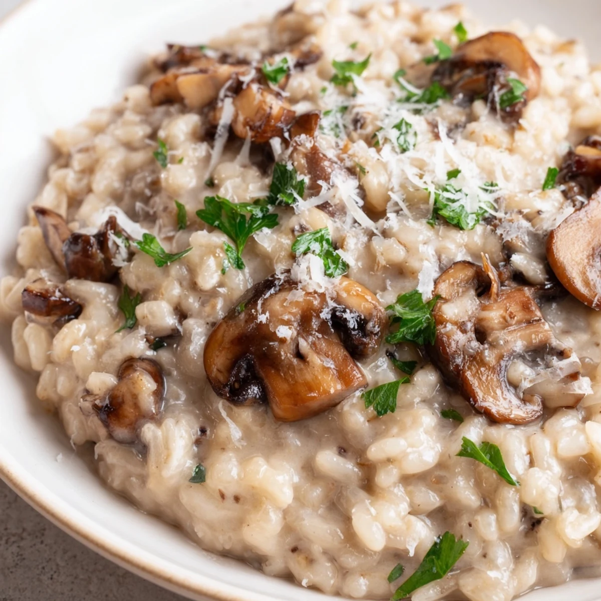 A spoon scoops Creamy Mushroom Risotto, showing a velvety texture with shaved Parmesan.