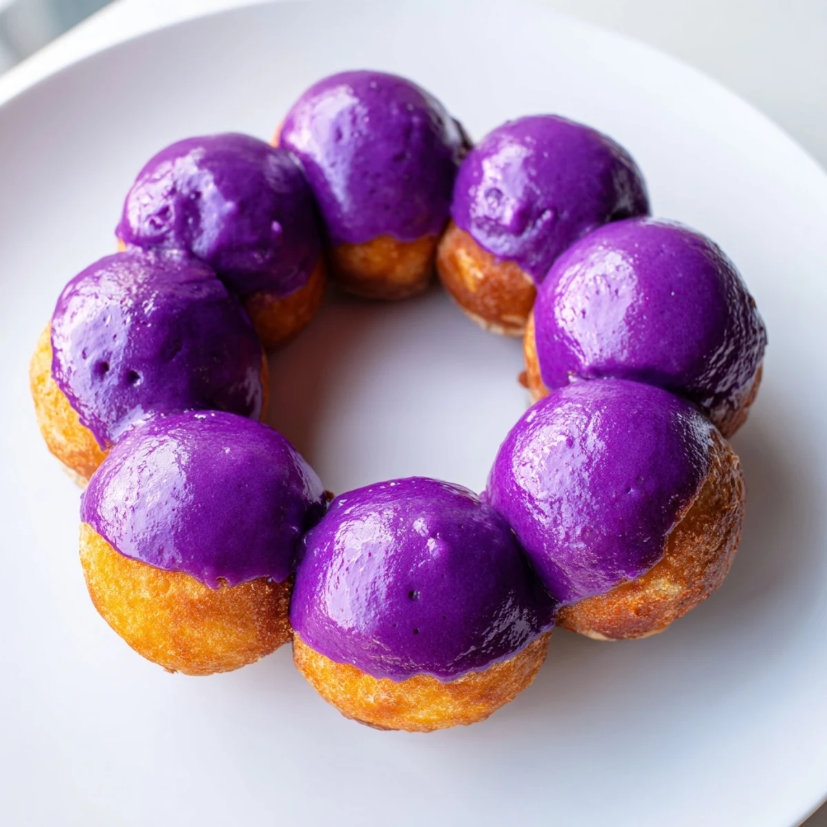 Warm ube mochi donuts drizzled with sweet ube glaze, ready to enjoy with a cup of coffee.