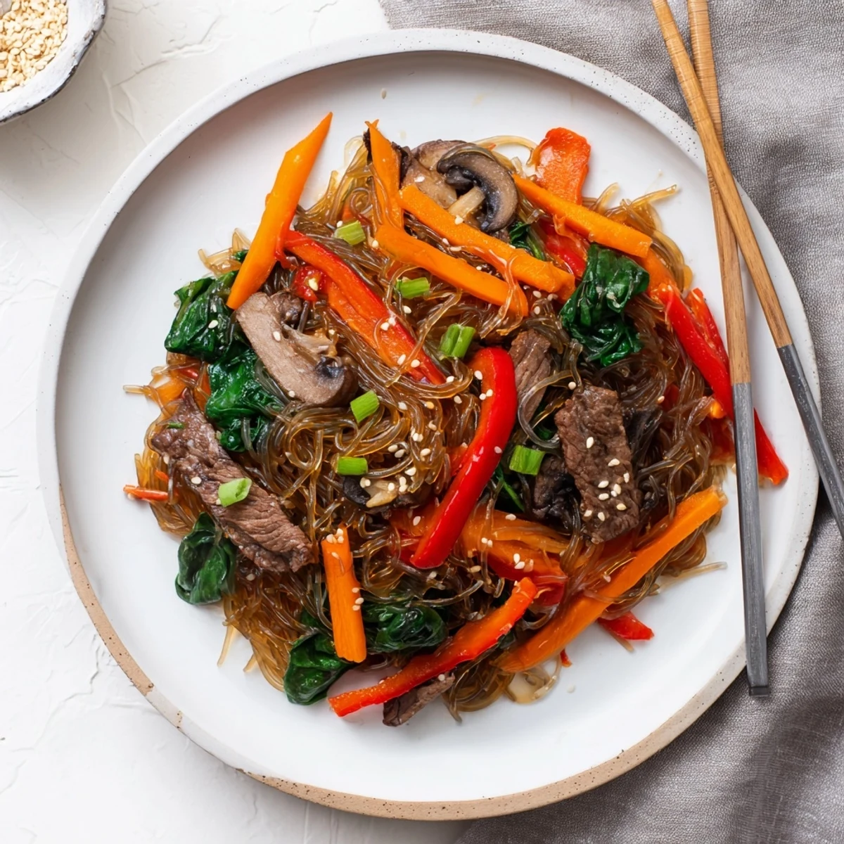Bright red bell peppers, julienned carrots, and green scallions top the savory Korean Beef Noodles dish for a vibrant weeknight meal.