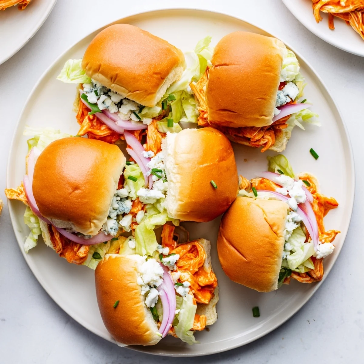 Spicy Buffalo Chicken Sliders on a platter with shredded chicken and blue cheese, ready to serve at a game day party.