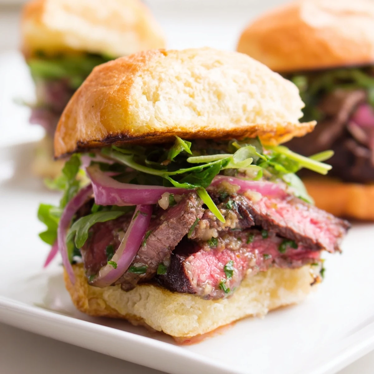 Warm Cowboy Butter Steak Sliders with juicy sliced steak on toasted buns and fresh arugula.