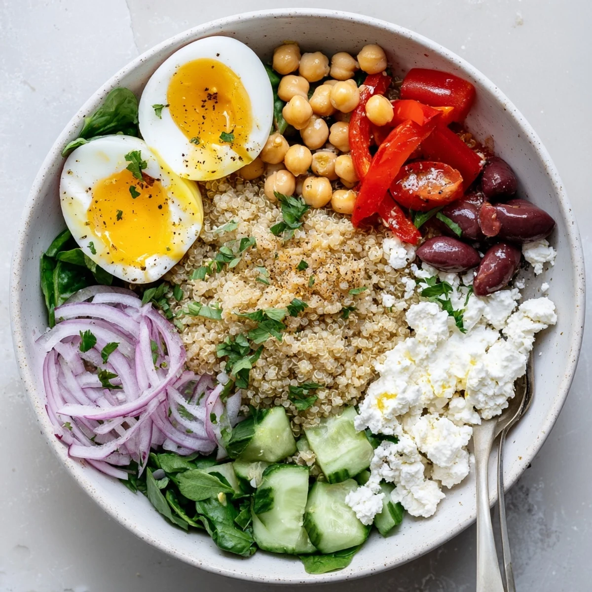 A close-up of High Protein Mediterranean Breakfast Bowls with jammy halved eggs and vibrant cherry tomatoes on quinoa.