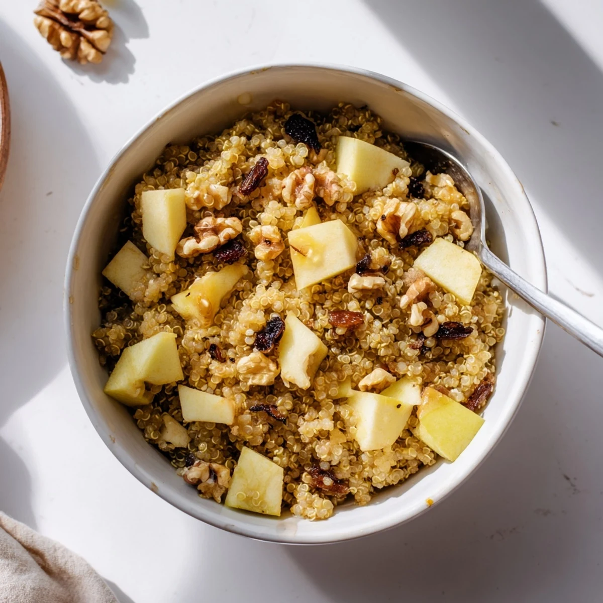 A cozy bowl of Healthy Quinoa Apple Breakfast sprinkled with cinnamon and drizzled with honey.