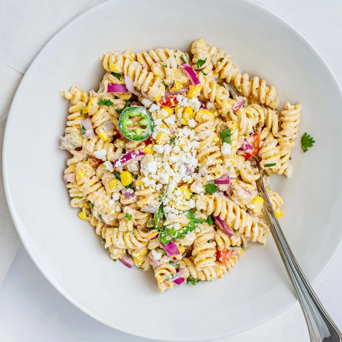 Juicy Street Corn Pasta Salad with charred corn kernels, creamy chili-lime dressing, and crumbled cotija in a vibrant bowl.