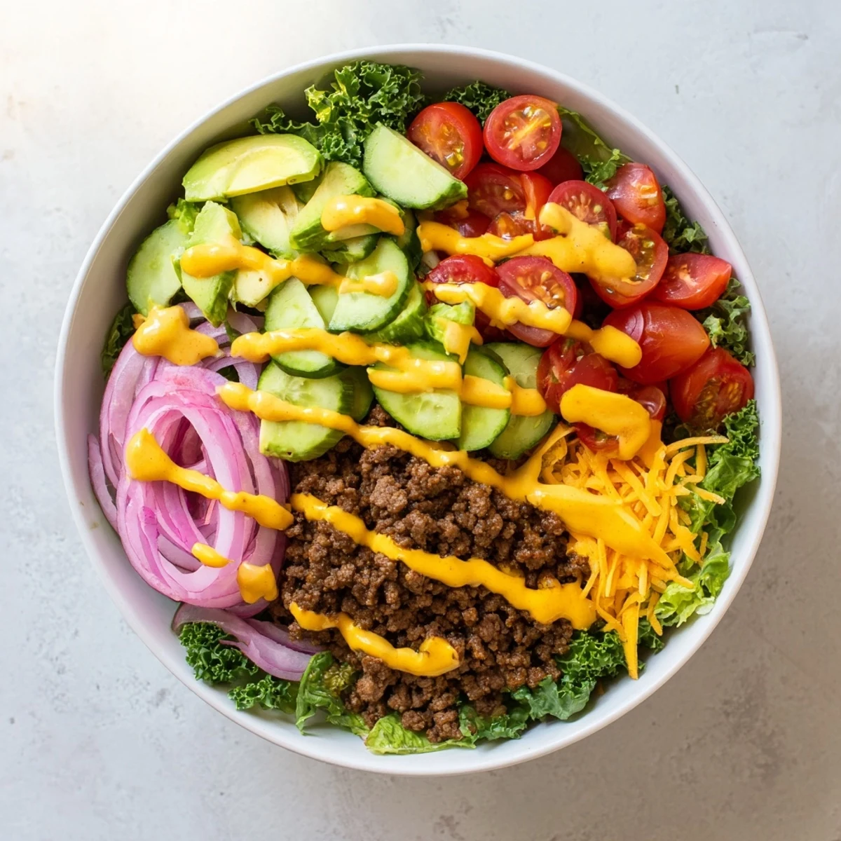 Freshly assembled Burger Bowls feature bright cherry tomatoes, red onion, and pickles with creamy burger sauce drizzled on top.  