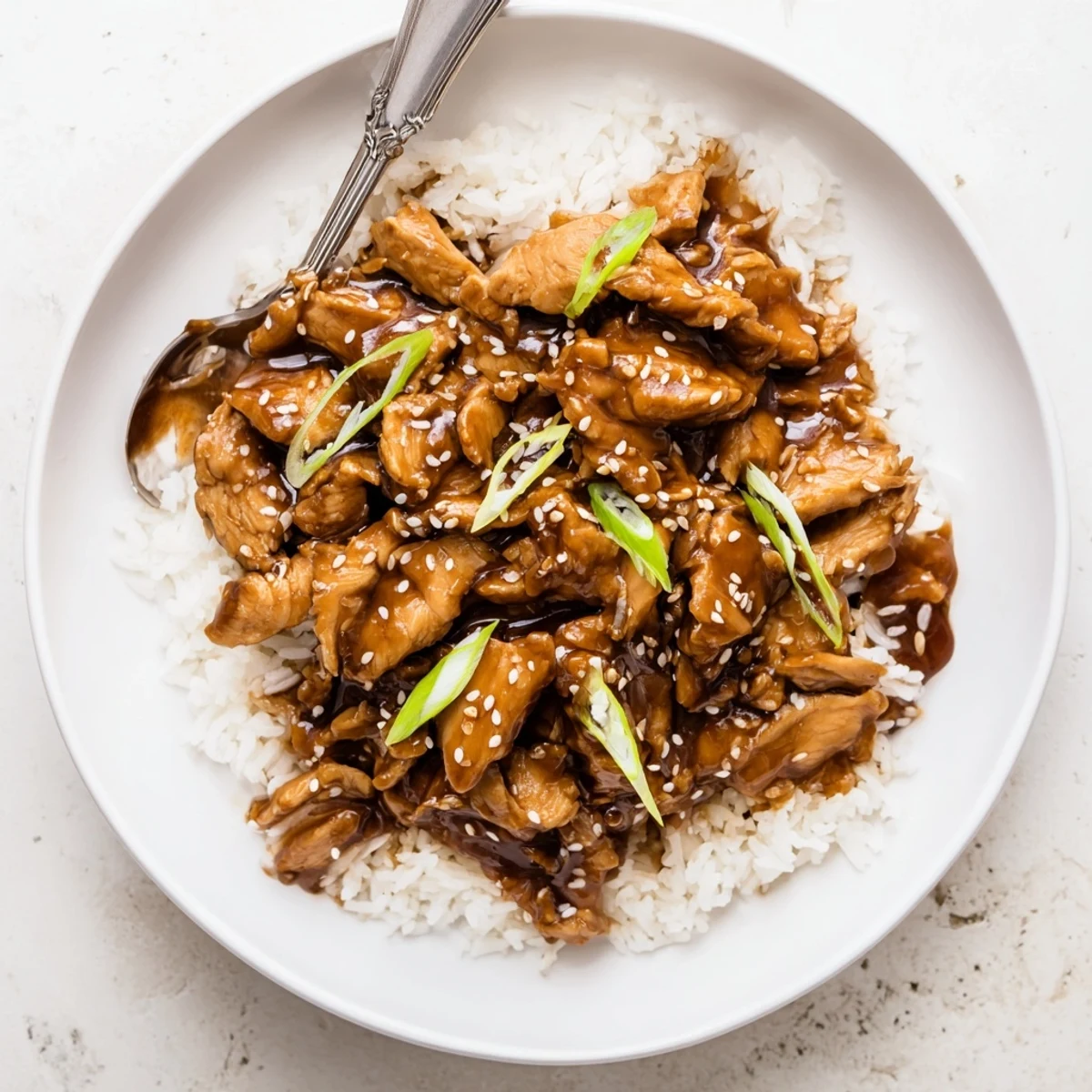 Shredded chicken thighs in rich savory-sweet Mongolian sauce garnished with green onions and sesame seeds