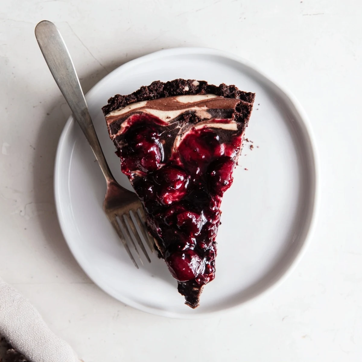 Creamy dark chocolate cherry cheesecake slice with glossy red cherry topping on chocolate crust
