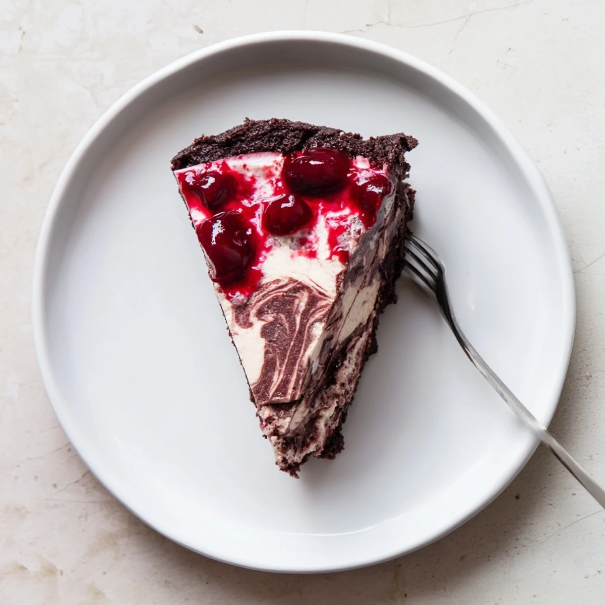 Rich dark chocolate cherry cheesecake drizzled with sweet cherries on a dessert plate