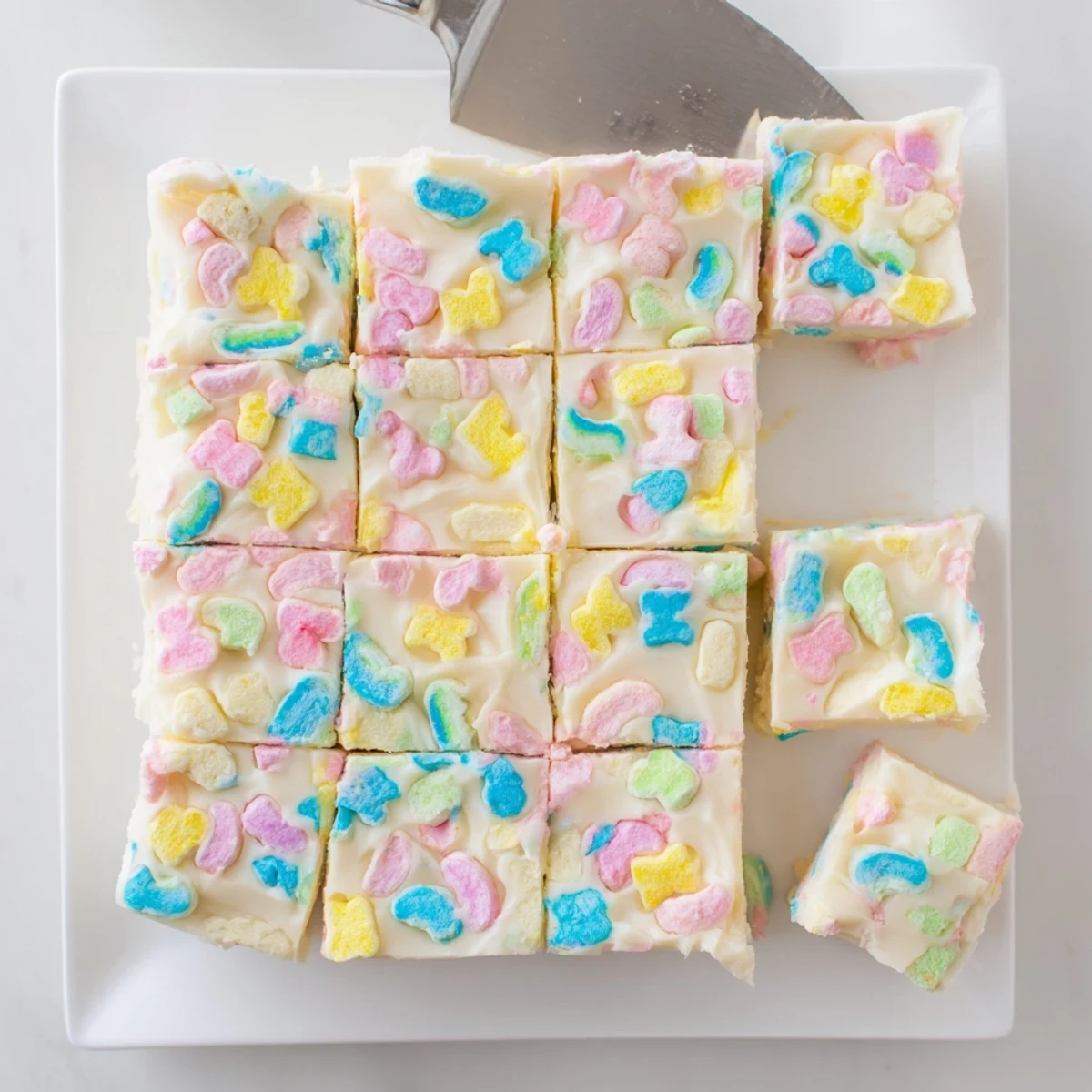 Creamy white chocolate Easy Lucky Charms Fudge topped with colorful marshmallow bits on a white plate.