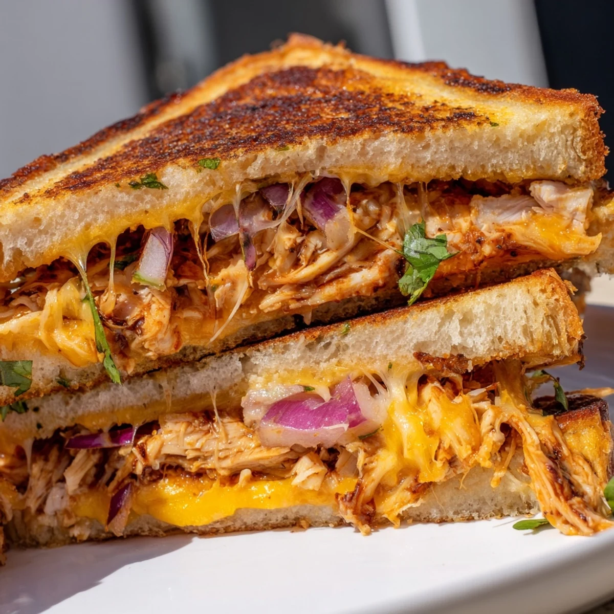 Plate of BBQ chicken grilled cheese sandwiches with red onion and fresh cilantro on a rustic wooden board