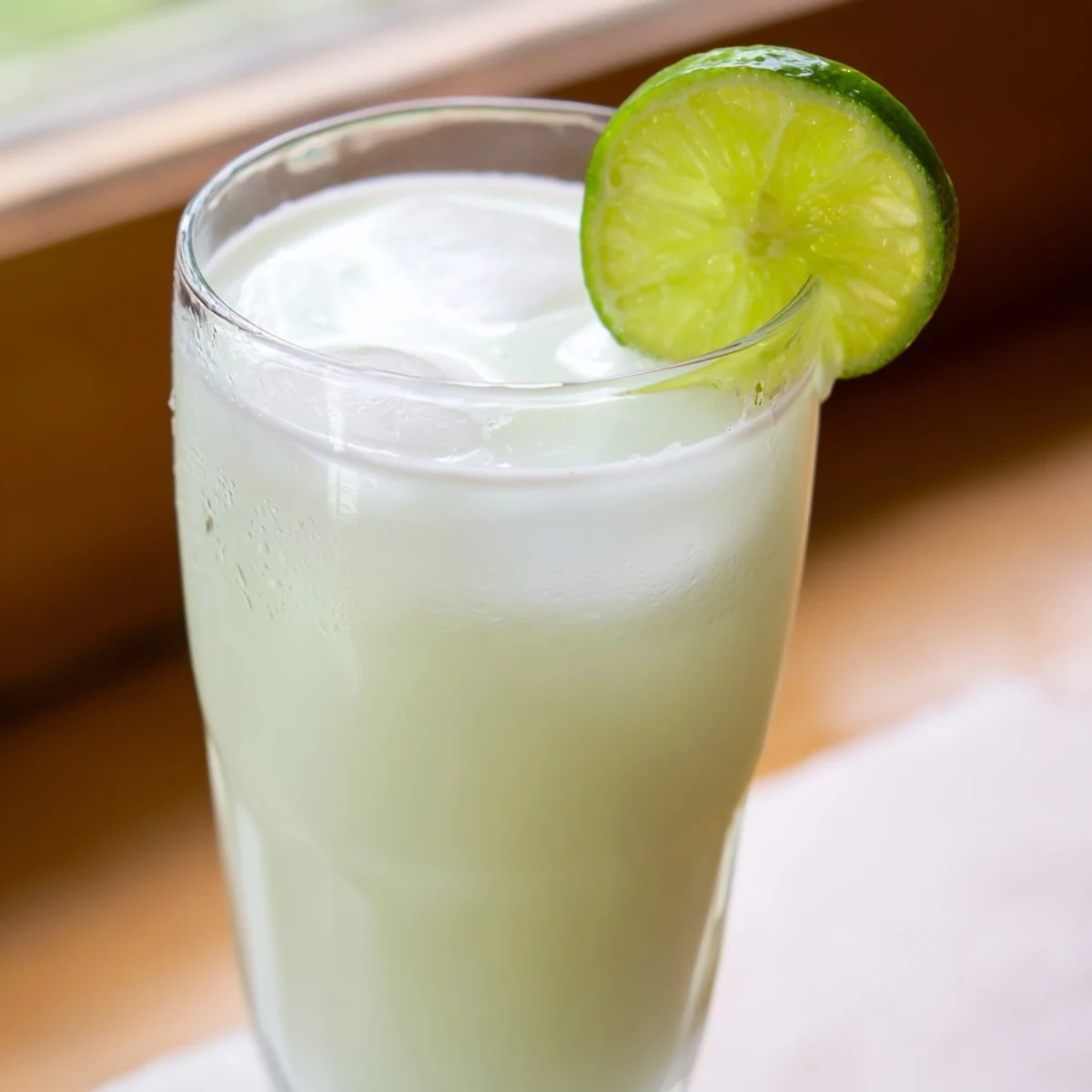 Tall chilled glass of Brazilian lemonade showing thick creamy texture and pale green color