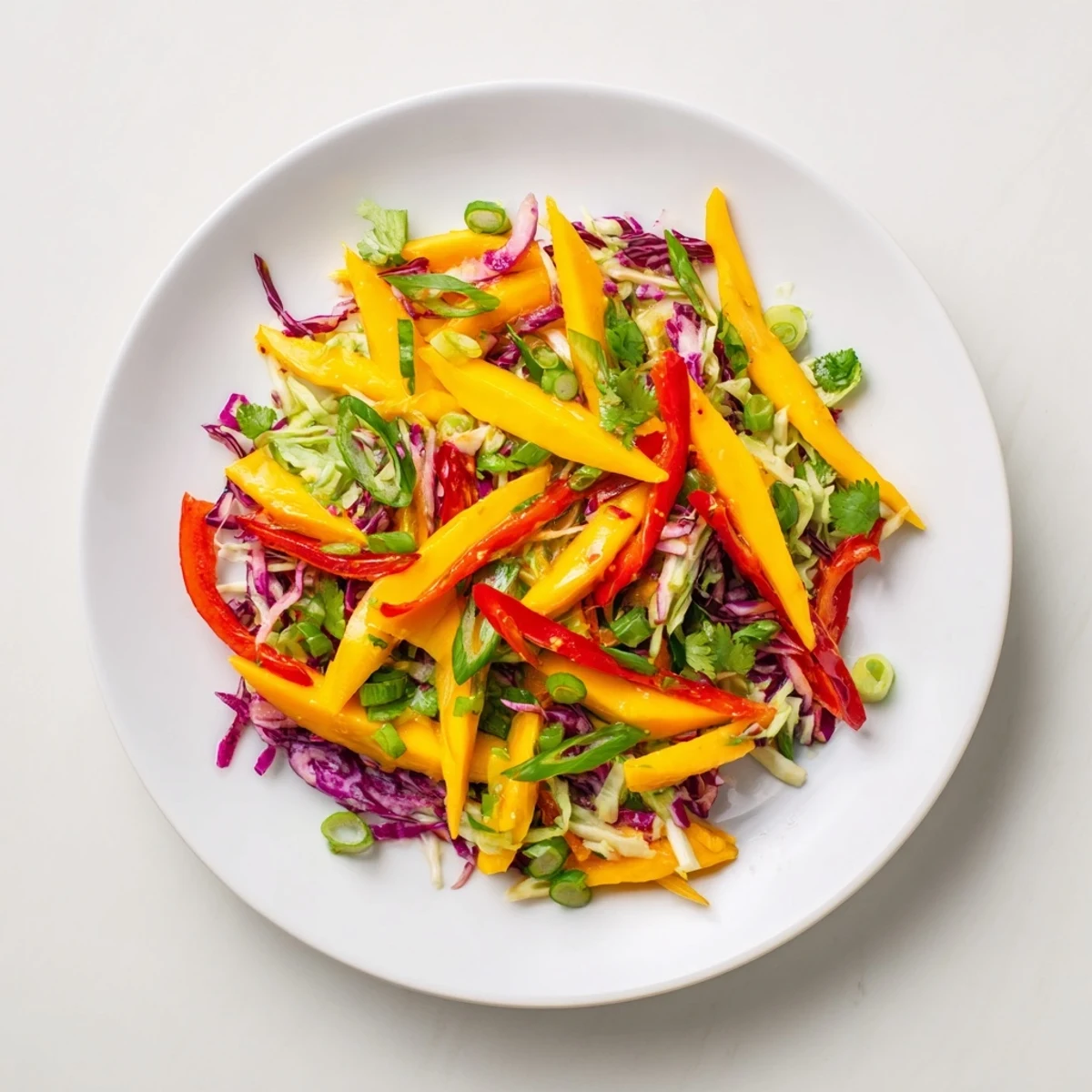 Vibrant mango slaw bowl with crisp red and green cabbage tossed in tangy lime dressing