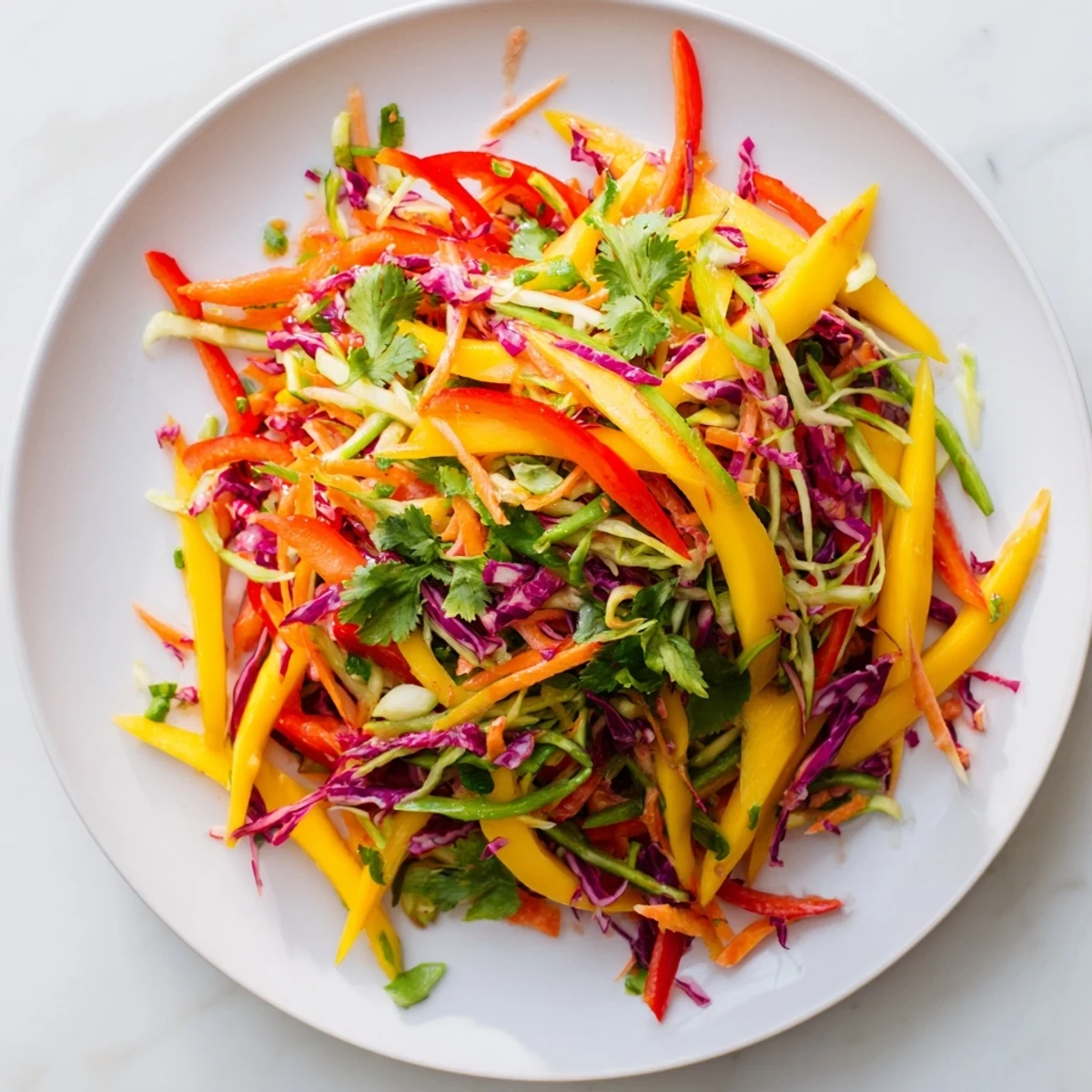 Fresh mango slaw topped with cilantro featuring julienned vegetables and colorful bell pepper strips
