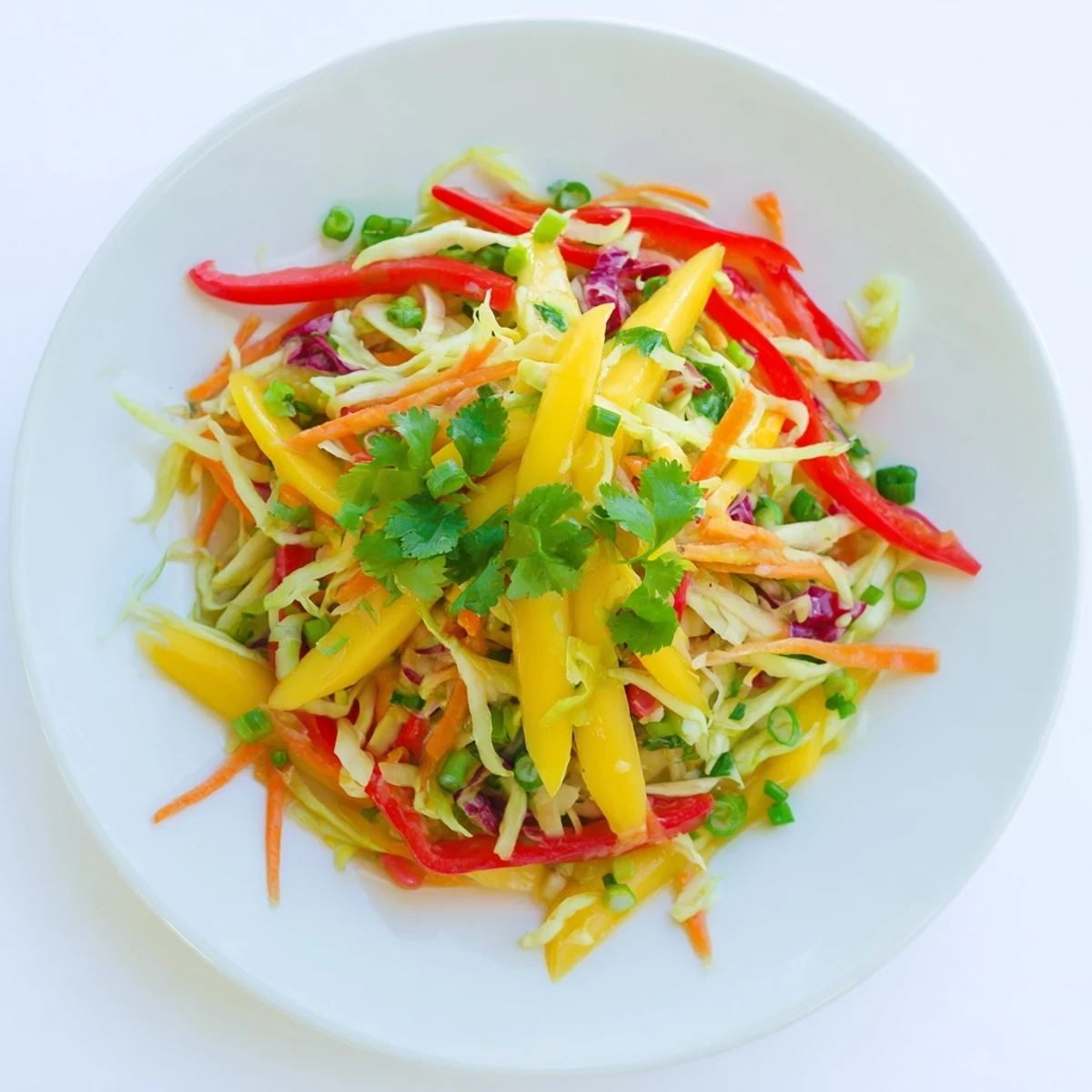 Golden mango slaw with shredded cabbage, carrots, and zesty lime dressing drizzled over crisp vegetables