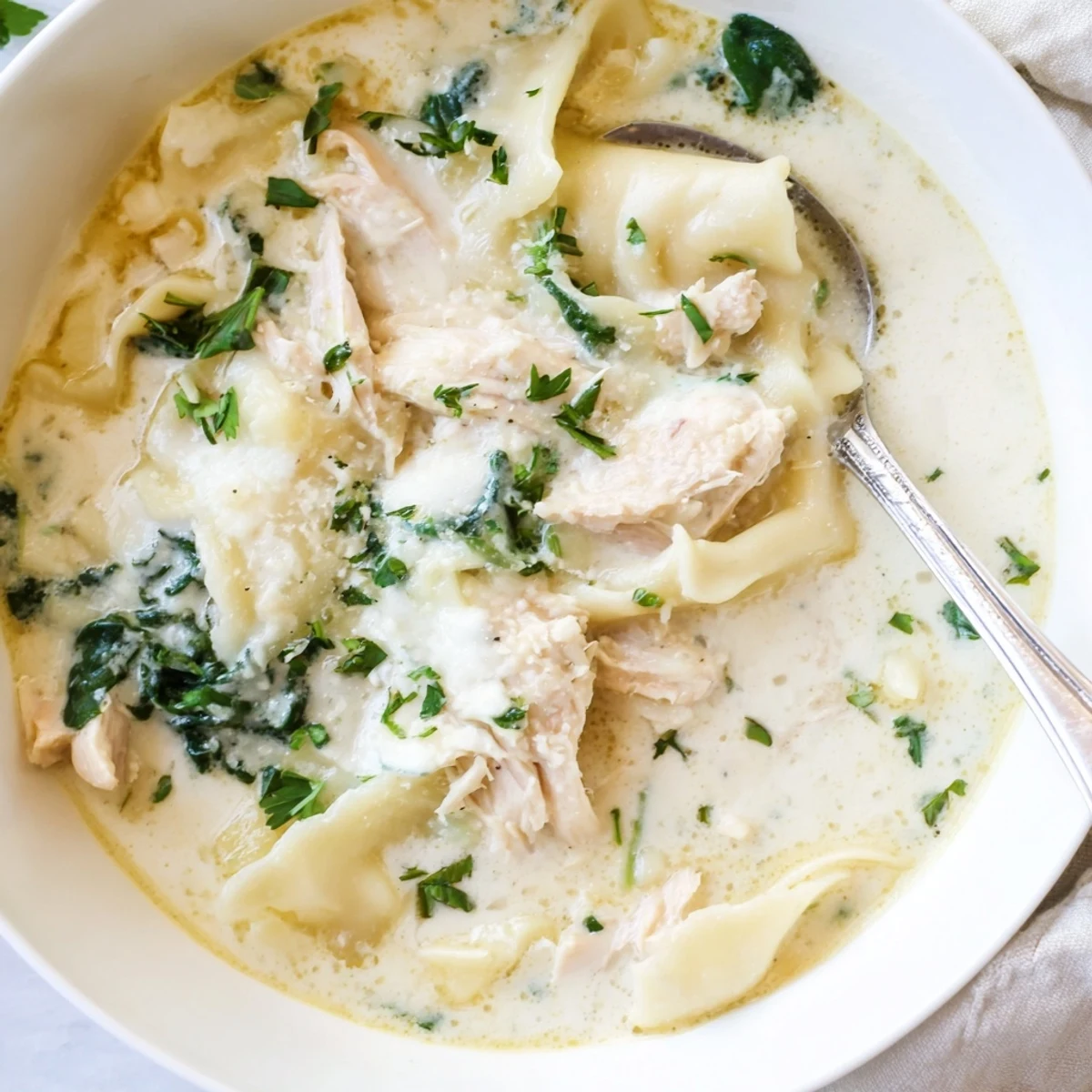Creamy white lasagna soup with tender chicken and spinach in a savory Parmesan broth