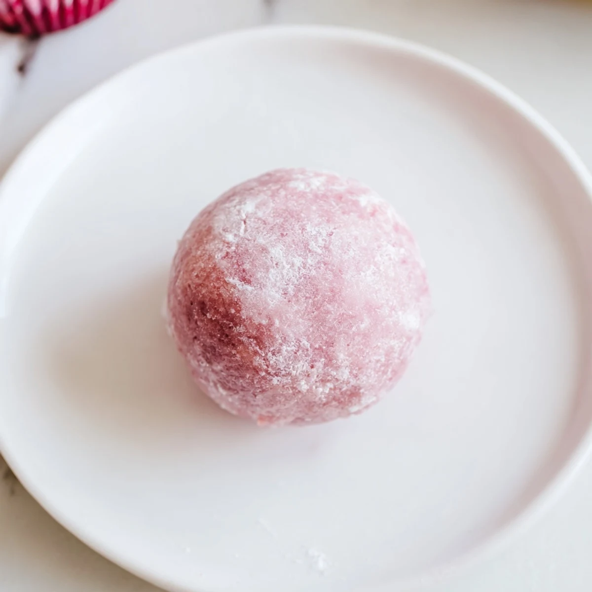 Chewy handmade mochi wrapped around creamy dairy-free strawberry ice cream on wooden board