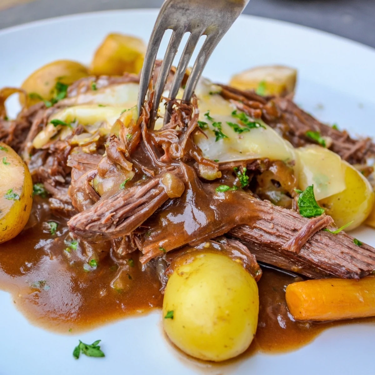 Fork-tender French onion pot roast served on a platter with roasted vegetables and a ladle of dark savory gravy