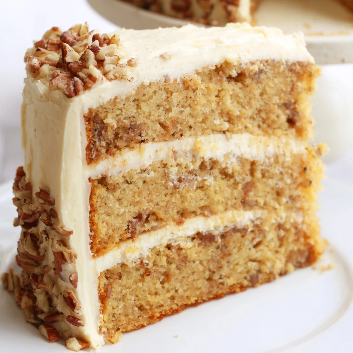 Slice of moist butter pecan cake revealing buttery pecans throughout the tender crumb under swirled buttercream