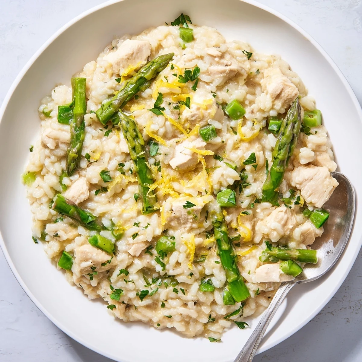 Golden chicken and green asparagus risotto garnished with lemon zest and cheese