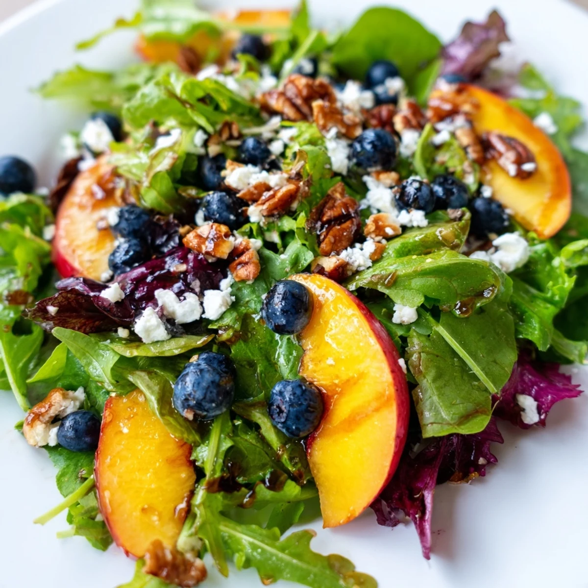 Summer blueberry peach feta salad featuring colorful fruit topping bed of leafy greens with tangy feta sprinkles