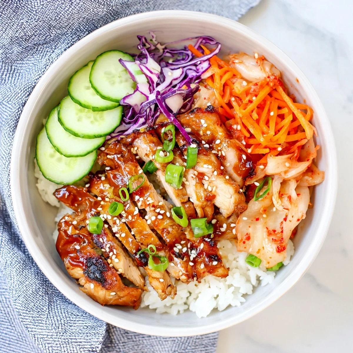 Savory Korean BBQ chicken thighs sliced over rice with crisp cucumber and carrots