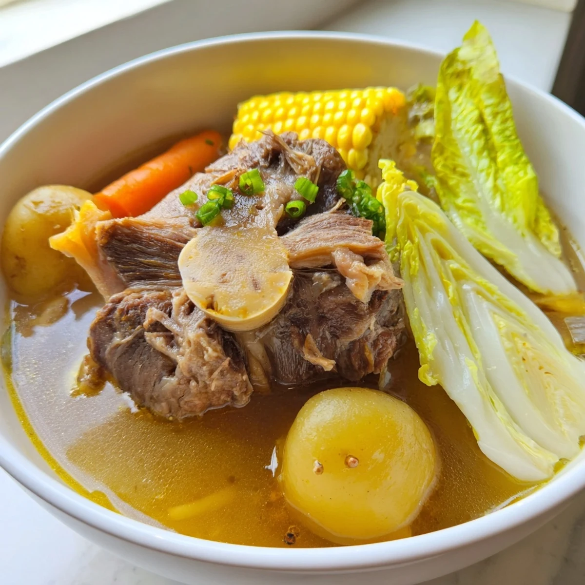 Filipino Bulalo beef shank soup featuring succulent meat bone marrow and fresh corn pieces