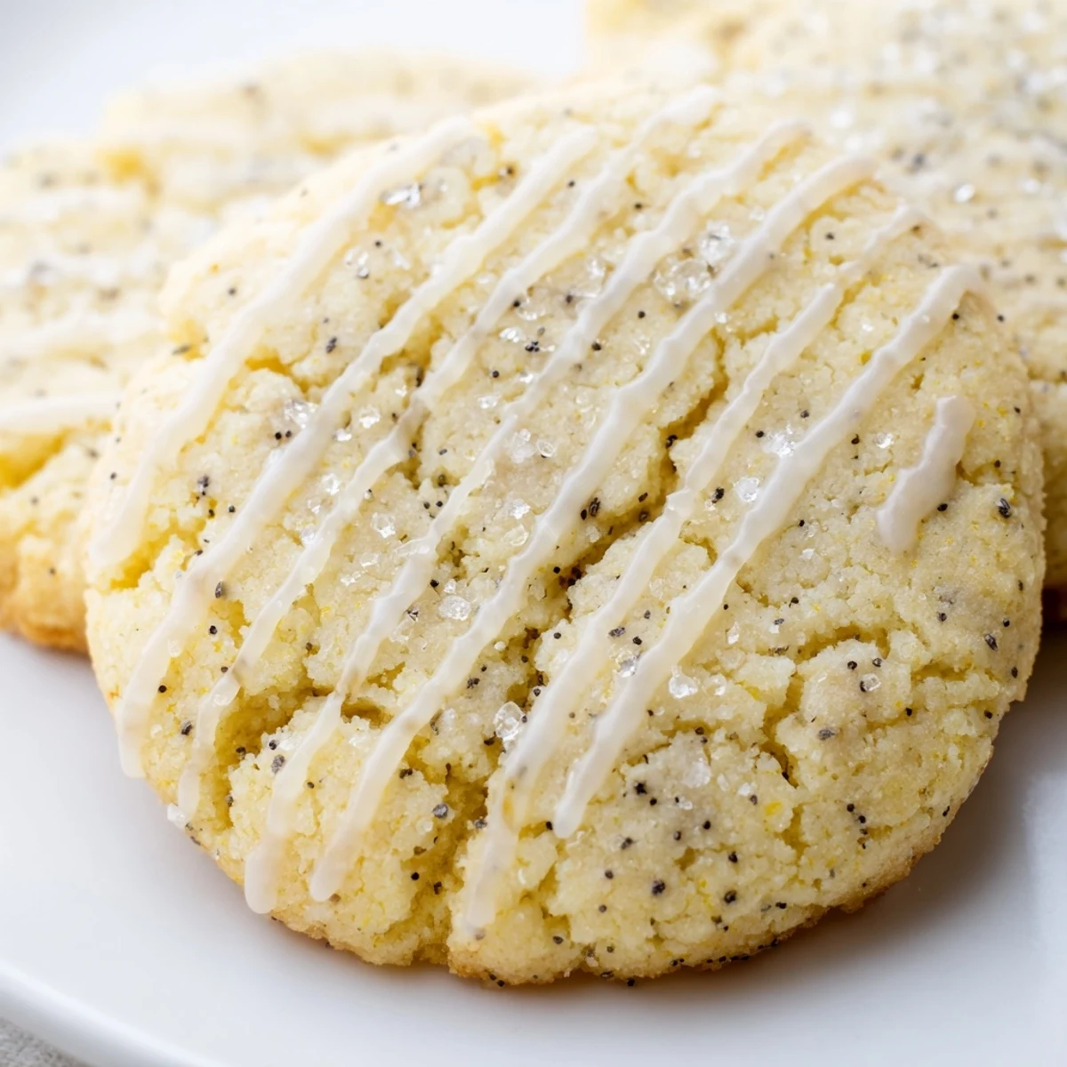 Golden lemon poppy seed cookies with drizzled glaze arranged on a rustic white serving plate