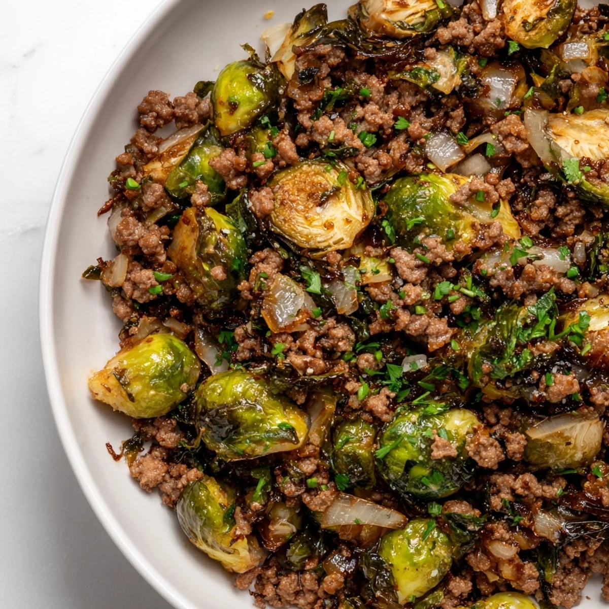 Ground Beef Brussels Sprouts recipe served steaming hot with fresh parsley garnish on white plate