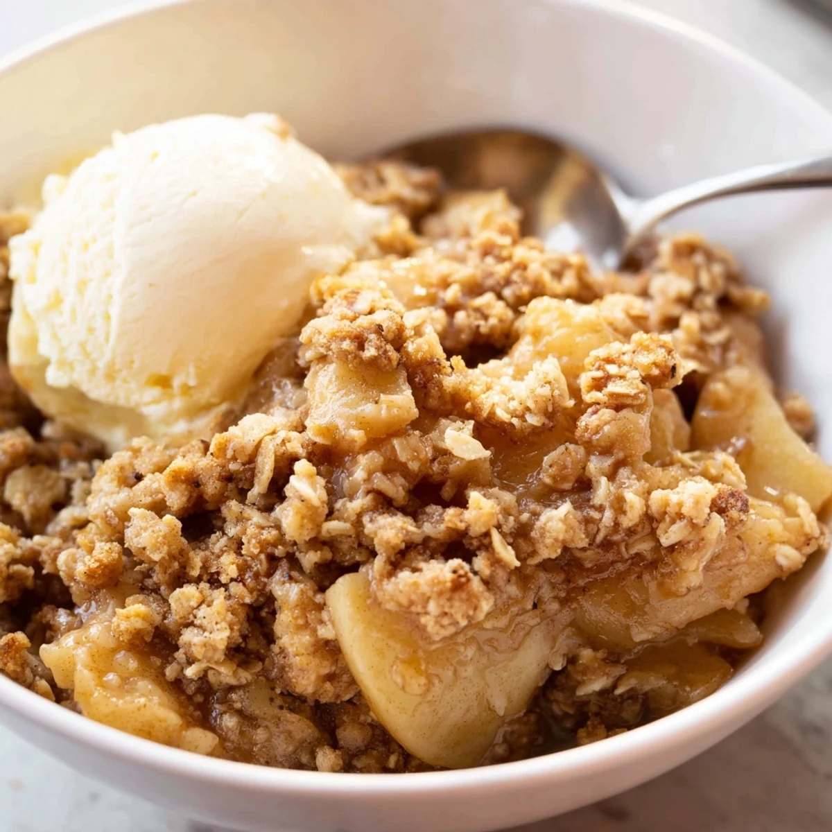 Crockpot apple crisp topped with a buttery crumble next to a scoop of vanilla ice cream