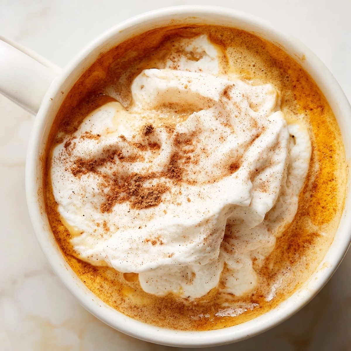 Creamy homemade pumpkin spice latte topped with whipped cream and cinnamon dusting