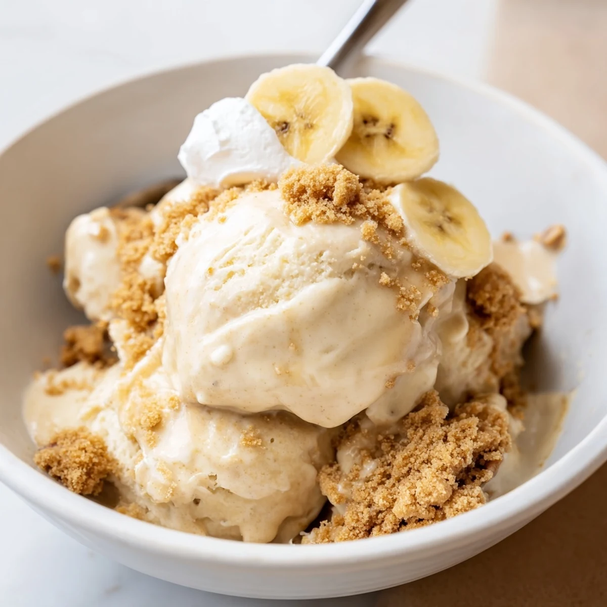 Freshly spun Ninja Creami Banana Cream Pie Ice Cream topped with whipped cream