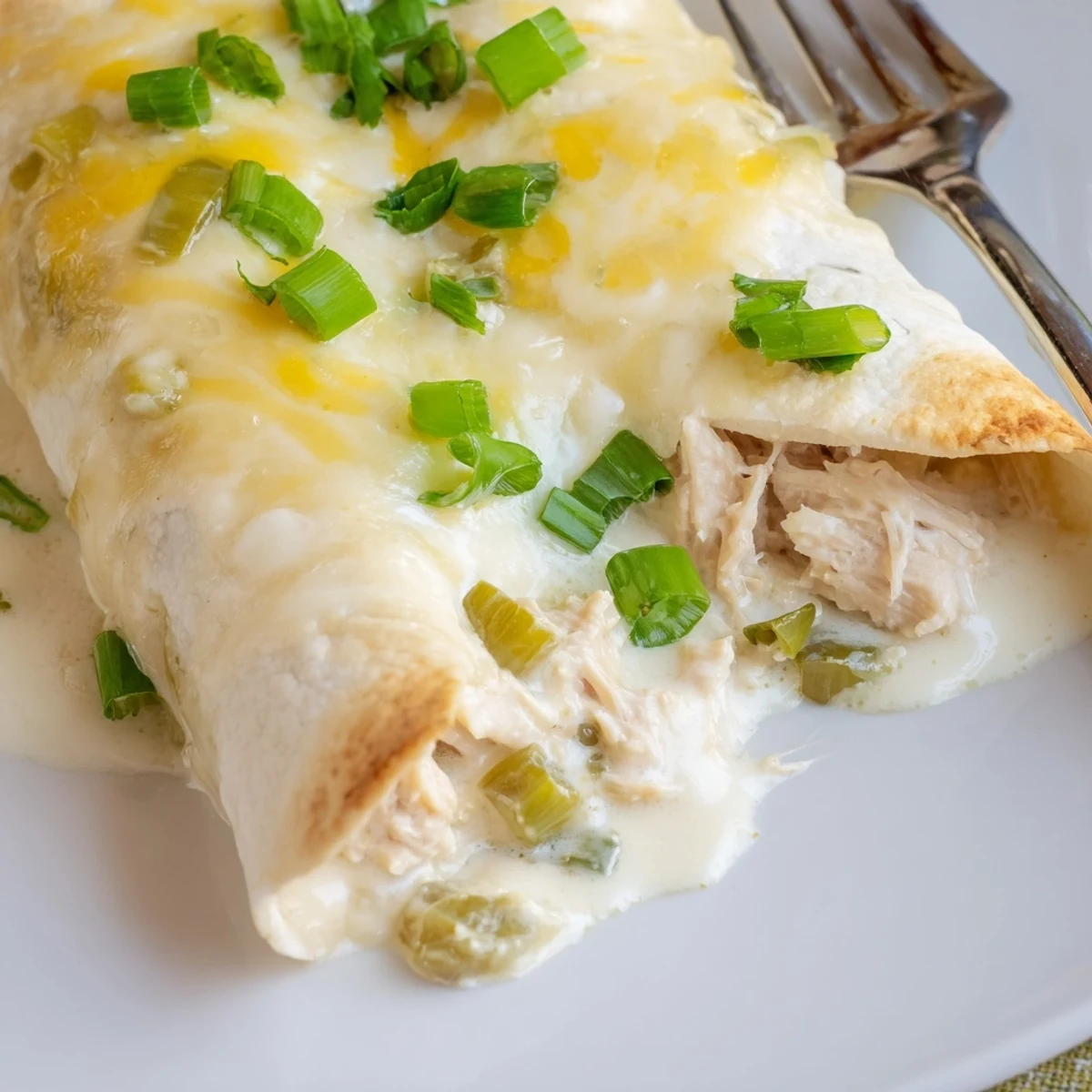 Creamy White Rotisserie Chicken Enchiladas bubbling in a cheese-topped baking dish